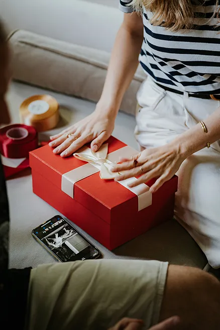 Photo of a woman wrapping a gift and a man sitting next to her